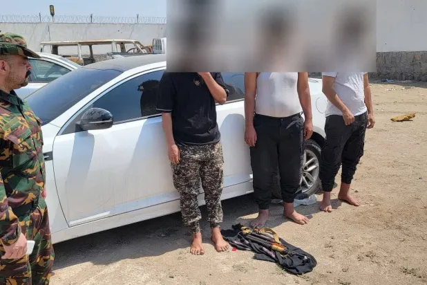 رجل أمن يقف بجوار عدد من أفراد الخلية التي تتهمها أجهزة الأمن اليمنية بالتخطيط لاغتيالات (الحكومة اليمنية)