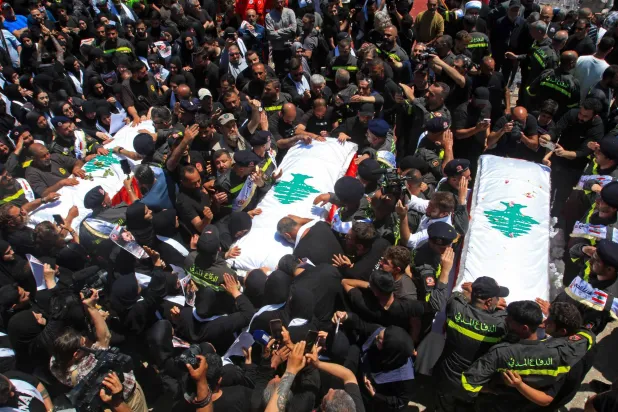 مشيِّعون يشاركون في جنازة 3 عناصر من الدفاع المدني قُتلوا بغارة إسرائيلية في جنوب لبنان (أ.ف.ب)