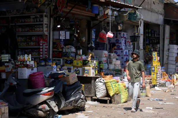 An Iraqi man walks past shops in the Jamila food market in Sadr City, east Baghdad on April 13, 2026. (AFP)