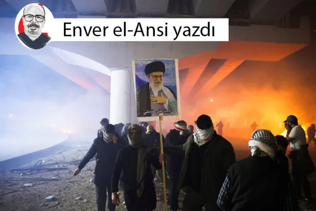 Irak'ın Bağdat şehrindeki Yeşil Bölge'de, Iraklı Şii silahlı grupların destekçileri ABD Büyükelçiliğine doğru yürüyüş yapmaya çalışırken, bir protestocu merhum İran Dini Lideri Ali Hamaney'in resmini taşıyor (Reuters)