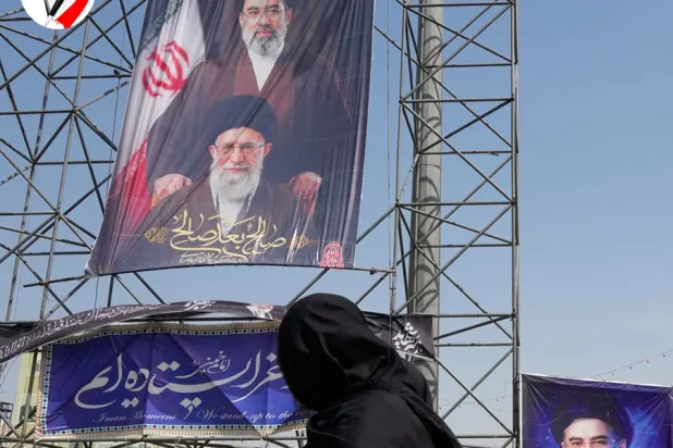 Tahran'da bir kadın, ABD-İsrail saldırılarında öldürülen baba Ali Hamaney ile oğlu Mücteba Hamaney’e ait afişlerin önünden geçiyor (AP)