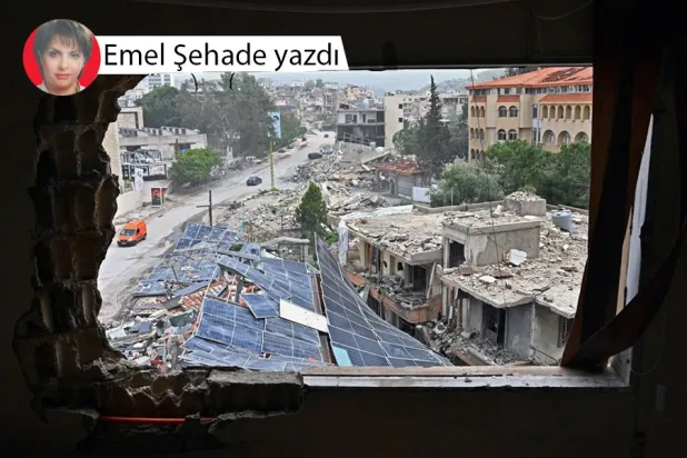 Yerinden edilmiş sakinler, güney Lübnan'daki Nebatiye kentine dönerken yıkılmış binaların yanından geçiyor (AFP)