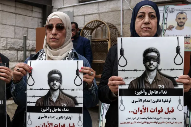 Protesters hold placards outside the Red Cross offices in Ramallah, in the Israeli-occupied West Bank, on March 31, 2026, during a rally against a bill approved by Israel's parliament that would allow the execution of Palestinians convicted on terror charges for deadly attacks. (AFP via Getty Images) 