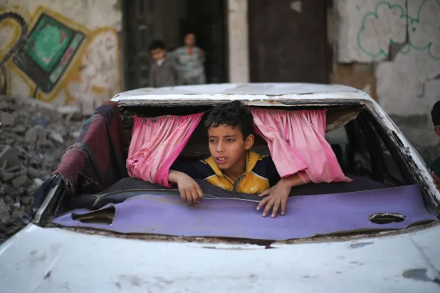 A displaced Palestinian child play inside a car destroyed during the Israel-Hamas war in the Bureij refugee camp, in the central Gaza Strip on May 1, 2026. (AFP)