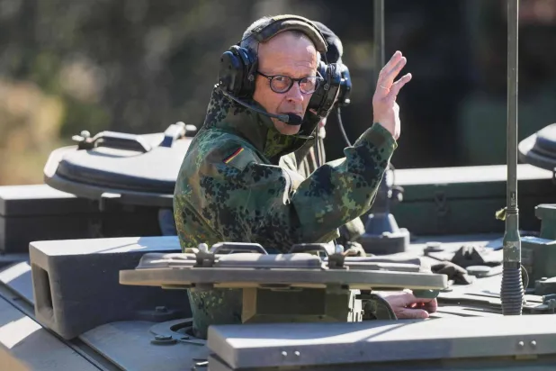 المستشار الألماني لدى زيارته لمعسكر في منستر شمال ألمانيا يوم 30 أبريل (أ.ف.ب)