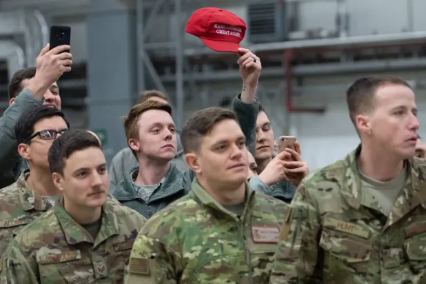 Aralık 2018'de Ramstein Hava Üssü'nde Başkan Trump ve First Lady için düzenlenen resepsiyonda bir Amerikan askeri, MAGA logosunu taşıyan şapkayı havaya kaldırıyor (AFP)