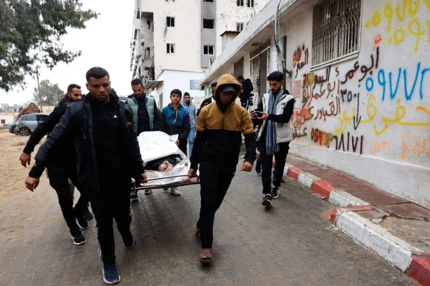 فلسطينيون يحملون قريباً لهم إلى أحد مستشفيات قطاع غزة (أ.ف.ب)