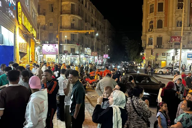 الناس يسيرون في شوارع وسط القاهرة ليلاً (أ.ف.ب)