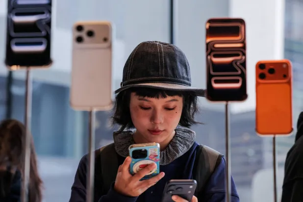 FILE PHOTO: A woman uses her smartphone inside the Apple store in Beijing's Sanlitun area as the new iPhone 17 series smartphones go on sale in Beijing, China September 19, 2025. REUTERS/Maxim Shemetov/File Photo