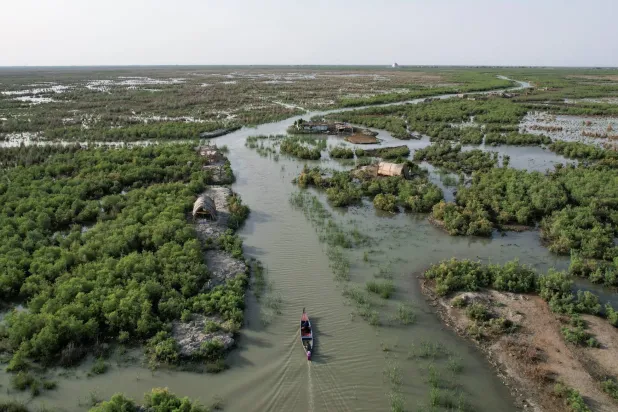 A drone view shows a boat moving through water channels amid vegetation at the Chibayish marshes in Dhi Qar province, Iraq, May 7, 2026. REUTERS/Thaier Al-Sudani