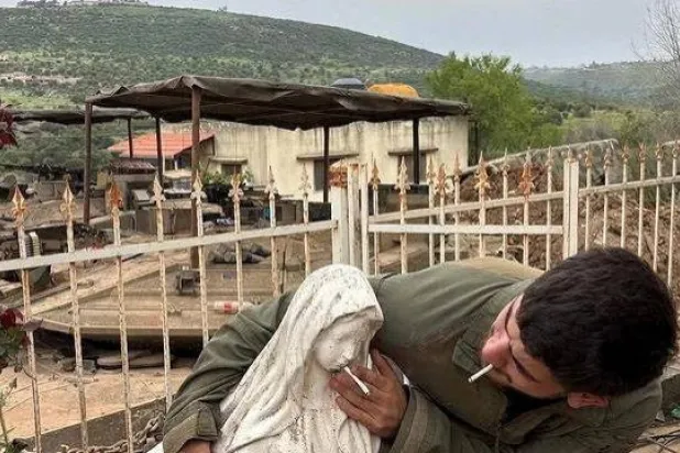 جندي إسرائيلي يضع سيجارة في فم تمثال السيدة العذراء في بلدة دبل بجنوب لبنان (رويترز)