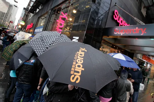 FILE - People cue in the rain waiting for the grand opening of the Superdry store in New York's Times Square, on May 9, 2012. (AP Photo/Richard Drew, File)