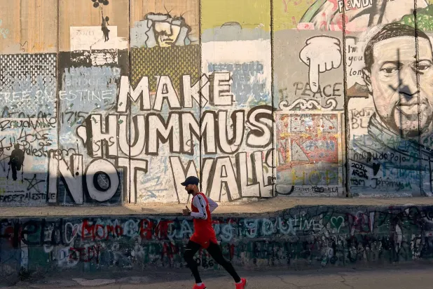  Palestinian Mohamad Al-Assi, who was released from Israeli detention six months ago, runs past Israel's separation wall as he trains ahead of the Palestine Marathon in the West Bank city of Bethlehem, Thursday, May 7, 2026. (AP) 