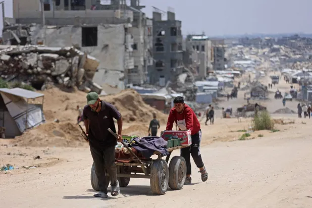 فلسطينيون نازحون ينقلون صناديق في عربة عبر أنقاض المباني المدمرة في جباليا شمال قطاع غزة (أ.ف.ب)