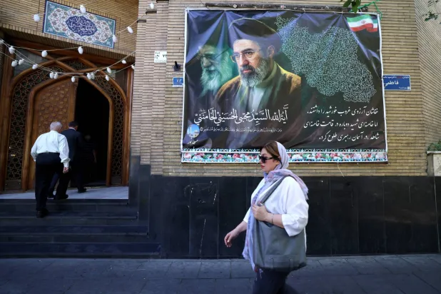 An Iranian woman walks a mosque decorated with a banner depicting Iran's current leader Mojtaba Khamenei, in the capital Tehran on May 9, 2026. (Photo by ATTA KENARE / AFP) / 