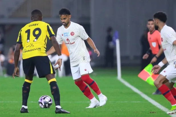 طارق عبدالله يحاول المرور من ديابي لاعب الاتحاد (موقع نادي ضمك)