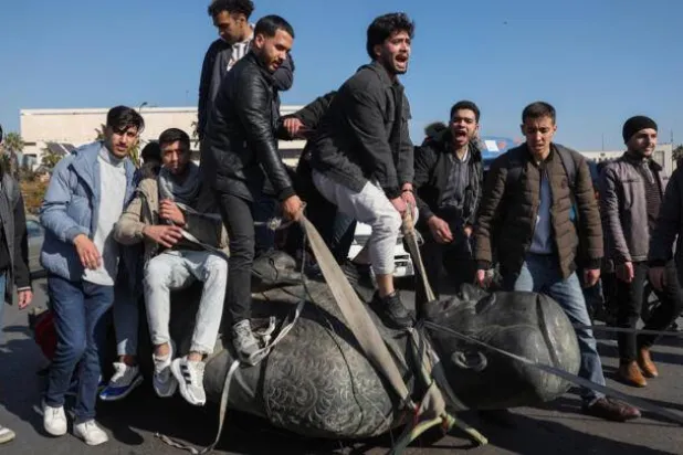 Students stand on the toppled statue of late president Hafez al-Assad during a rally near the campus of the Damascus University in the Syrian capital on December 15, 2024. Omar Haj Kadour, AFP
