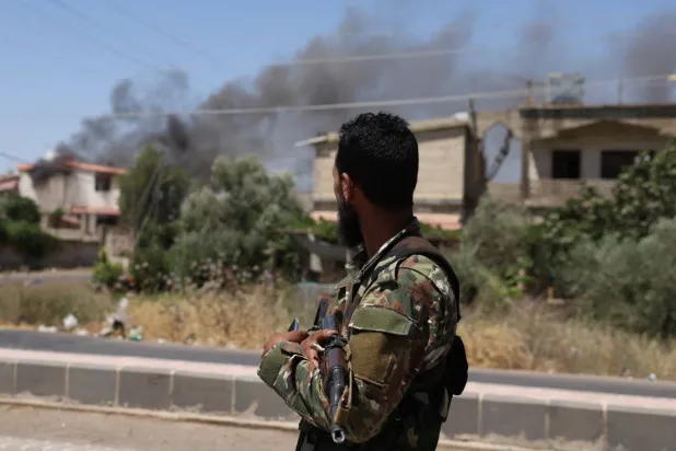 A member of Syria's security forces stands under a sign in the predominantly Druze city of Sweida on July 15, 2025. (AFP)