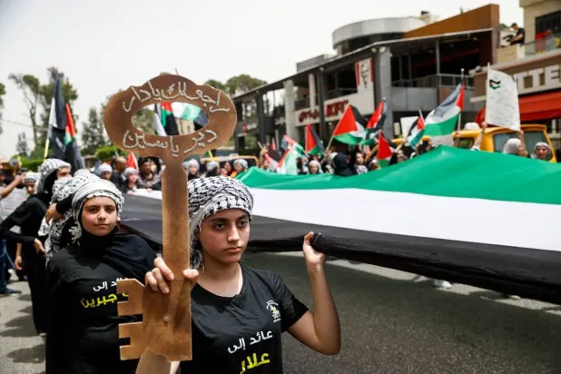 Palestinians carry a giant Palestinian flag as they take part in a rally to mark the 78th anniversary of the Nakba, in Ramallah, in the Israeli-occupied West Bank, May 12, 2026. (Reuters)
