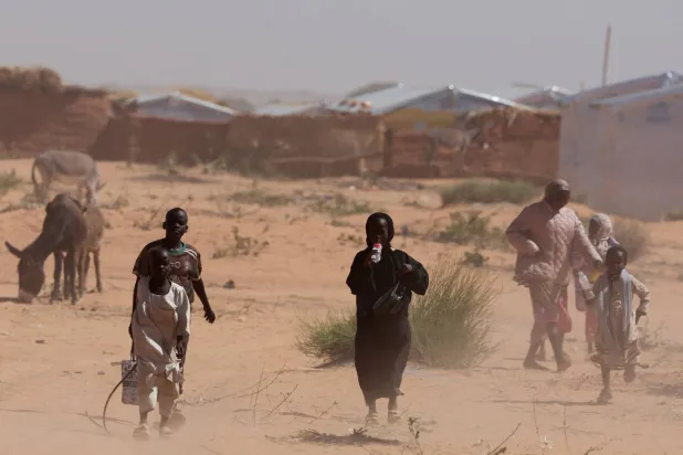 نازحون من دارفور يسيرون وسط عاصفة رملية في مخيم للاجئين السودانيين بشرق تشاد في 30 نوفمبر 2025 (رويترز)