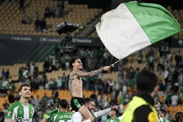 البرازيلي أنتوني نجم ريال بيتيس يلوّح بعلم الفريق احتفالاً بالتأهل لدوري الأبطال (أ.ف.ب)