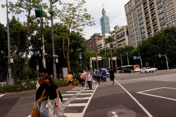 Taipei 101 rises in the background above residential buildings while people walk across a street in Taipei, Taiwan, May 12, 2026. REUTERS/Ann Wang