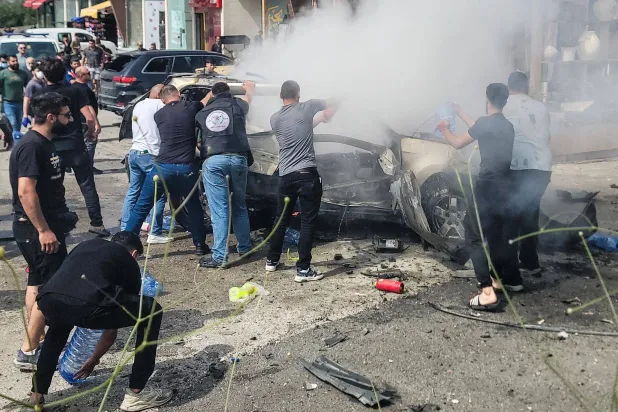 جهود لإطفاء سيارة تحترق بعد غارة نفذتها مسيّرة إسرائيلية في بلدة الجية جنوب بيروت (أ.ف.ب)