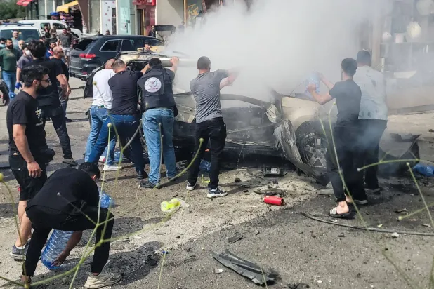 Beyrut'un güneyindeki Ciye kasabasında İsrail insansız hava aracı saldırısının ardından yanan bir aracı söndürme çalışmaları (AFP)