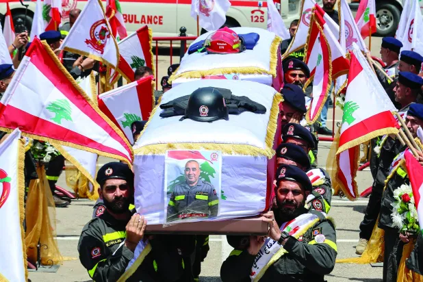 
عناصر من الدفاع المدني يحملون نعشين لزميلين لهما قتلا بغارة إسرائيلية الثلاثاء في جنوب لبنان (إ.ب.أ)