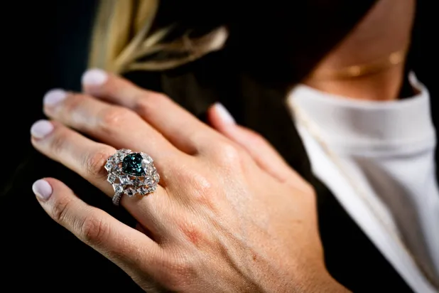 A Christie's employee displays "The Ocean Dream," the largest fancy vivid blue-green diamond, weighting 5.50 carats, during a preview at Christie's in Geneva, Switzerland, Thursday, May 7, 2026. (Jean-Christophe Bott/Keystone via AP)