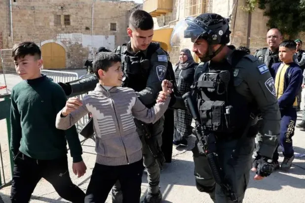 عناصر من الشرطة الإسرائيلية يعتقلون أطفالاً فلسطينيين في الخليل بالضفة الغربية (أ.ف.ب)
