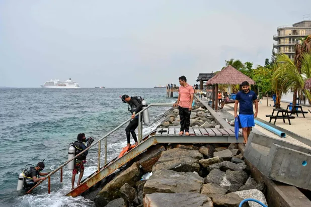 A tourist, along with guides, returns after an open-water diving session near Rasfannu Beach in Malé on May 15, 2026. (Photo by Mohamed Afrah / AFP)
