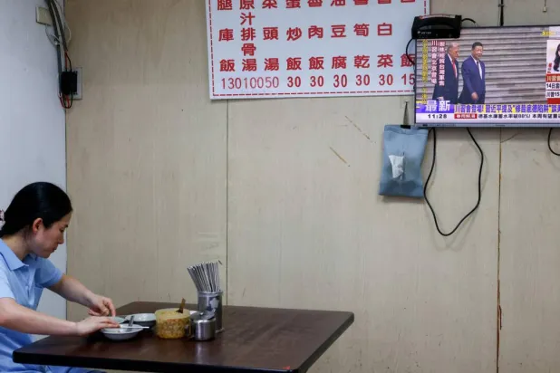 A television screen shows a live broadcast of the meeting between US President Donald Trump and Chinese President Xi Jinping, at a restaurant in Taipei on May 14, 2026. Ann Wang, Reuters
