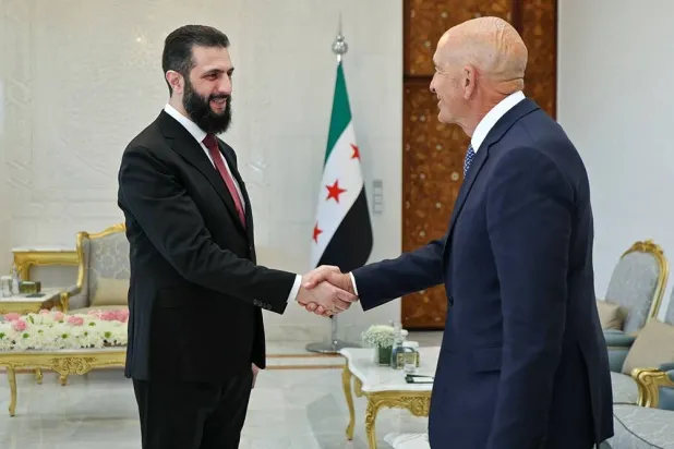 This handout photograph released by the Syrian Arab News Agency (SANA) on May 16, 2026 shows Syria's President Ahmed al-Sharaa (L) shaking hands with US Ambassador to Türkiye and Special Envoy for Syria Tom Barrack before their meeting at the People's Palace in Damascus. (SANA / AFP)  