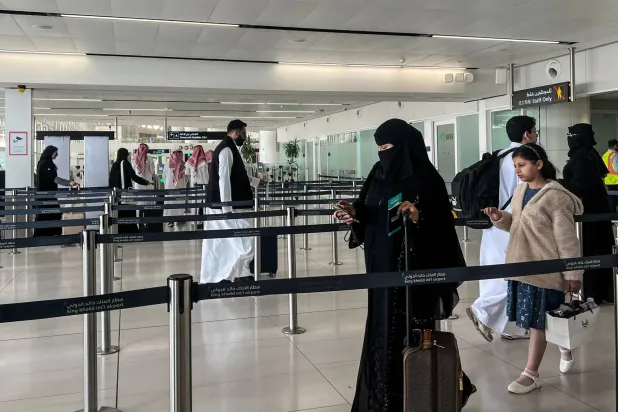 مسافرون عبر صفوف الحواجز في صالة المغادرة بمطار الملك خالد الدولي في الرياض (أ.ف.ب)
