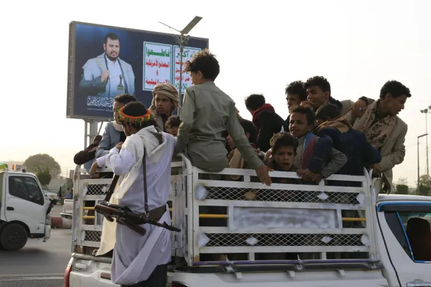 People ride a vehicle driving past a digital billboard featuring Houthi leader Abdul Malik al-Houthi in Sanaa, Yemen, 14 May 2026. (EPA) 