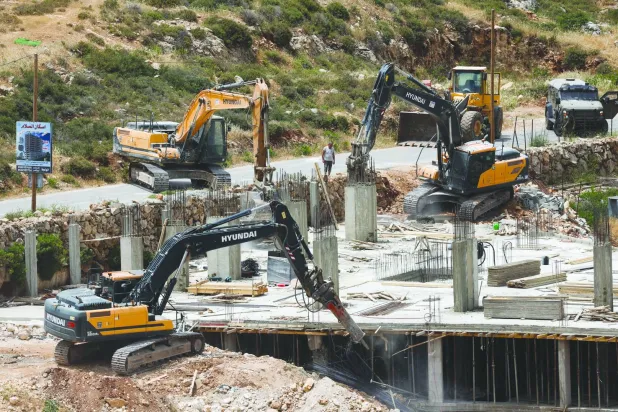
آليات إسرائيلية ثقيلة تهدم مبنى فلسطينياً قرب بيت لحم في الضفة الغربية المحتلة أمس (رويترز)