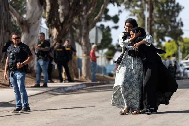 Two women react as they leave a reunification center following the shooting at the Islamic Center of San Diego in southern California, on May 18, 2026. (AFP)