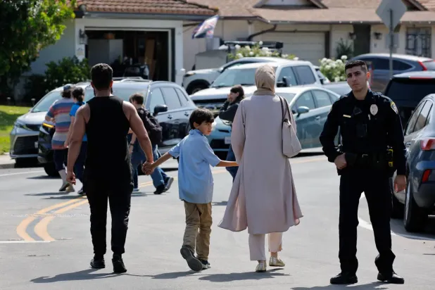 Kaliforniya’daki San Diego İslam Merkezi’nde meydana gelen silahlı saldırının ardından bir çocuk, camiden ayrılırken anne ve babasının ellerini tutuyor (Reuters)