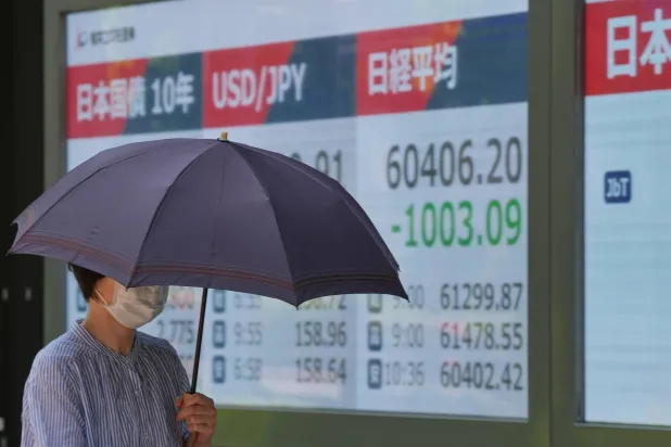 سيدة تمر أمام شاشة تعرض حركة الأسهم في وسط العاصمة اليابانية طوكيو (أ.ب)