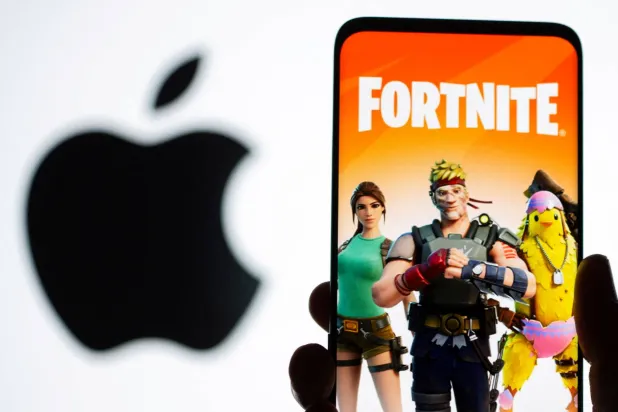صورة ترتبط بلعبة «فورتنايت» تظهر على شاشة هاتف ذكي أمام شعار «أبل» (رويترز)