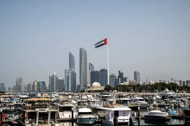 The United Arab Emirates flag flutters against the backdrop of the Abu Dhabi Skyline following a reported Iranian strike, March 1, 2026. (AFP)
