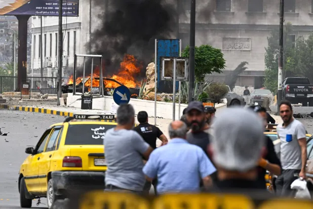 مدنيون يتابعون احتراق سيارة في موقع التفجير بدمشق الثلاثاء (أ.ف.ب)