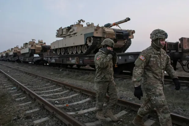 Amerikan askerleri, Romanya'daki Mihail Kogalniceanu Hava Üssü'nde M1 Abrams tanklarının yanında yürüyor (Arşiv- Reuters)