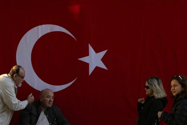 People are seen in front of a Turkish national flag hanged on a wall to mark the 101th anniversary of the Turkish Republic’s foundation a head of the Republic Day, in Istanbul, Türkiye, October 28, 2024. (Reuters) 