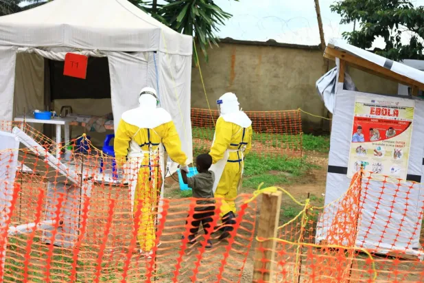 Demokratik Kongo Cumhuriyeti’nin doğusunda Ebola virüsüne yakalandığından şüphelenilen bir çocukla birlikte yürüyen sağlık görevlileri, 9 Eylül 2018. (AP)