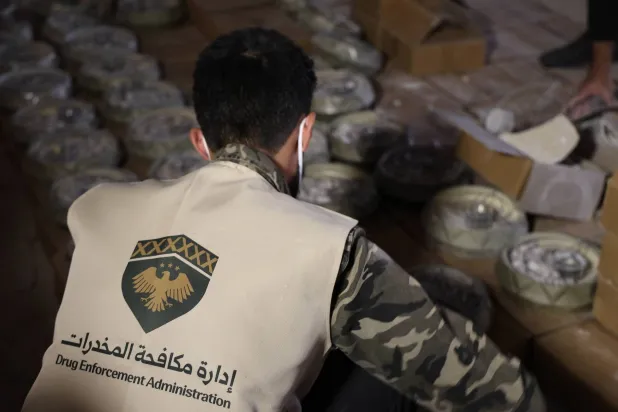 موظف في «إدارة مكافحة المخدرات» في سوريا يفحص صناديق تهريب شحنة الكبتاغون (الداخلية السورية)
