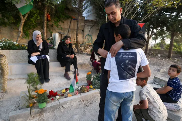 الفلسطيني سامح اشتية والد يوسف سامح اشتية البالغ من العمر 15 عاماً الذي قُتل في 23 أبريل على يد جنود إسرائيليين في مدينة نابلس يعانق ابنه في أثناء زيارتهما لقبر ابنه يوسف في مقبرة قرية تل غرب نابلس في الضفة الغربية المحتلة 12 مايو 2026 (أ.ف.ب)
