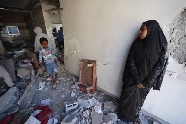 نازحون فلسطينيون يتفقدون الأضرار التي لحقت بأحد المنازل جراء غارة إسرائيلية في مخيم المغازي للاجئين وسط غزة يوم الخميس (أ.ف.ب)