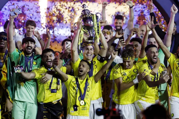 رونالدو يرفع كأس الدوري السعودي عاليا (رويترز)